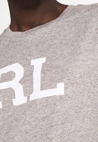 Grå bomullsblandning t-shirt med stora vita blockbokstäver "RL" på br östet. Mjuk textur med en klassisk rundhalsdesign.