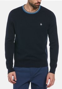 Pull bleu marine avec un col rond côtelé orné de rayures bleues et blanches, logo sur la poitrine gauche, et manches longues avec poignets côtelés.