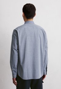 Chemise à manches longues à boutonnière à carreaux bleus et blancs, avec un col classique et des poignets boutonnés. Fabriquée en tissu en coton léger.