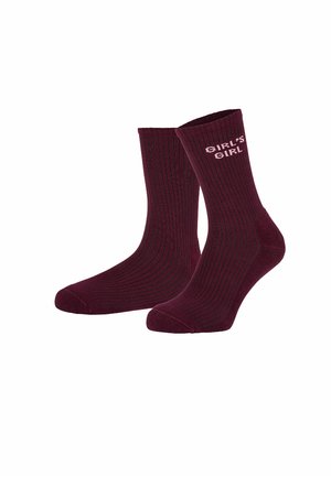 Par af mørkerøde ribstrikkede ankelsokker med teksten "GIRL'S GIRL" i lyserød nær øverste kant på den ene sok.