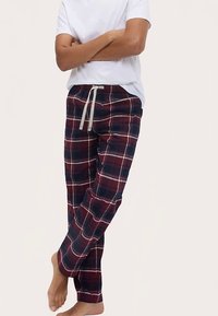 Geruite pyjamabroek in marineblauw, rood en wit, met een trekkoordsluiting en zachte katoenen stof. Volledig lange, recht gesneden pasvorm.