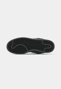 Svart sneaker sula med ett strukturerat mönster som har zigzag-ränder och en kontur som liknar en abstrakt fotform.