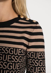 Maglia a maniche lunghe a righe beige e nero con motivo logo sull'orlo e dettagli con bottoni dorati sulla spalla.