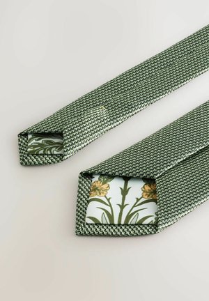 Green woven tie with a textured pattern. Interior features floral print in yellow and green on a light background. Triangular ends.