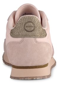 Różowe zamszowe sneakersy z teksturowanym szarym zapiętkiem, minimalistyczny design oraz jasnobrązową gumową podeszwą z małymi flekami.