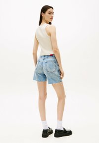 Lys beige ribbet tanktop parret med slidte lyseblå denimshorts. Sorte loafers og hvide sokker fuldender outfittet.