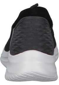 Sneaker nera con upper testurizzato, linguetta e suola bianca a contrasto con motivo a onda. Materiale flessibile per comfort e vestibilità.