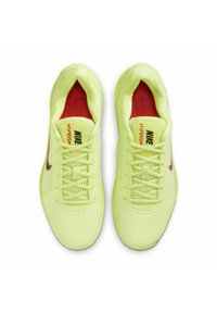 Scarpe da ginnastica gialle brillanti con tomaia in rete, dettagli rossi e logo Nike nero. Presentano un design con lacci e suola testurizzata per una maggiore aderenza.