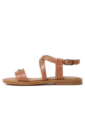 Sandale plate marron avec bride à la cheville, clous dorés sur l’orteil et la bride, et une petite fermeture à boucle sur fond blanc.