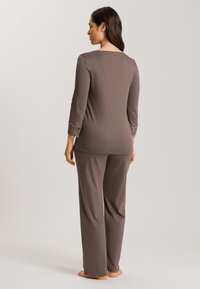 Brun loungewear-set som har en topp med trekvartslånga ärmar som är accentuerade med spets vid ärmsluten och löst sittande matchande byxor.