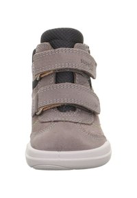 Zapato alto de ante gris con dos tiras de velcro, tobillo de textil negro y suela de goma blanca. Presenta acentos de costura verde.