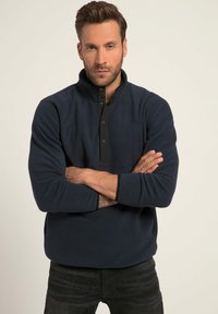 Pullover in felpa navy con patta a bottoni neri, maniche lunghe e tessuto texture. Presenta un logo sul petto e una vestibilità rilassata.