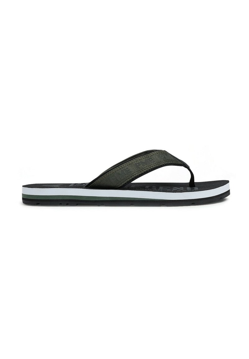 Zwarte en olijfgroene slipper met een gestructureerde band, vlakke zool en subtiele witte en donkergroene accenten aan de onderkant.