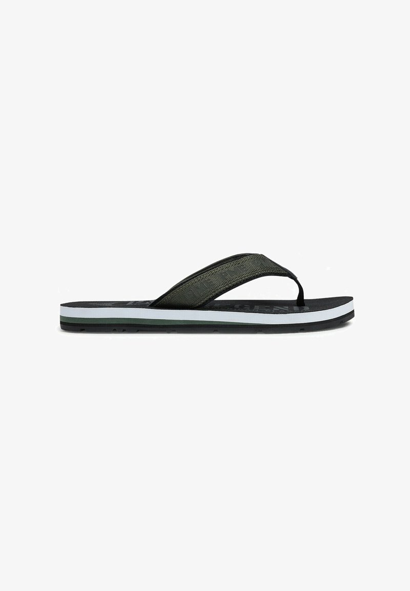 Zwarte en olijfgroene slipper met een gestructureerde band, vlakke zool en subtiele witte en donkergroene accenten aan de onderkant.