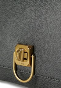 Schwarze strukturierte Lederhandtasche mit einem goldfarbenen Metallverschluss und Beschlägen, auf dem der Markenname "PICARD" eingraviert ist.