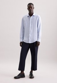 Camicia a righe blu chiaro e bianco con bottoni, abbinata a pantaloni navy scuri e scarpe eleganti nere, con colletto classico e maniche lunghe.