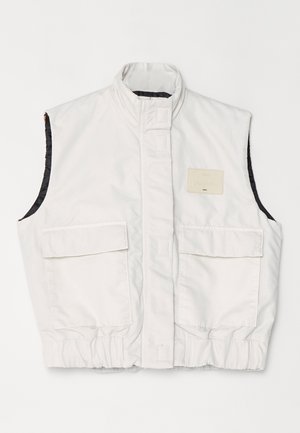 Weißes ärmelloses Oberteil mit hohem Kragen, zwei Fronttaschen und einem leicht strukturierten Stoff. Enthält ein quadratisches Etikett auf der Brust.