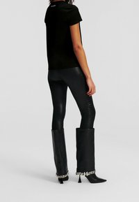 Black fitted t-shirt, short sleeves, paired with shiny black skinny pants. Chunky black boots with a silver chain accent at the top.
