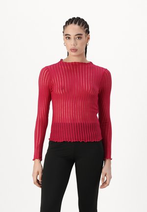 Red long-sleeve top with vertical stripes, textured fabric, scalloped hem and collar, worn with black pants. Transparent sections visible.