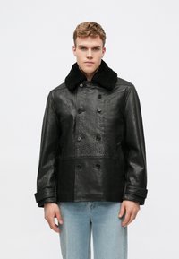 Veste noire en cuir double boutonnage avec une finition texturée et un col en shearling noir. Comprend des boutons et des poches latérales.