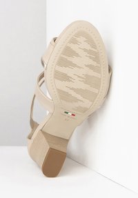 Beige højhælet sko med en tekstureret sål, der har tynde stropper og en firkantet hæl. "Made in Italy" label synlig på sålen. Størrelse 37.