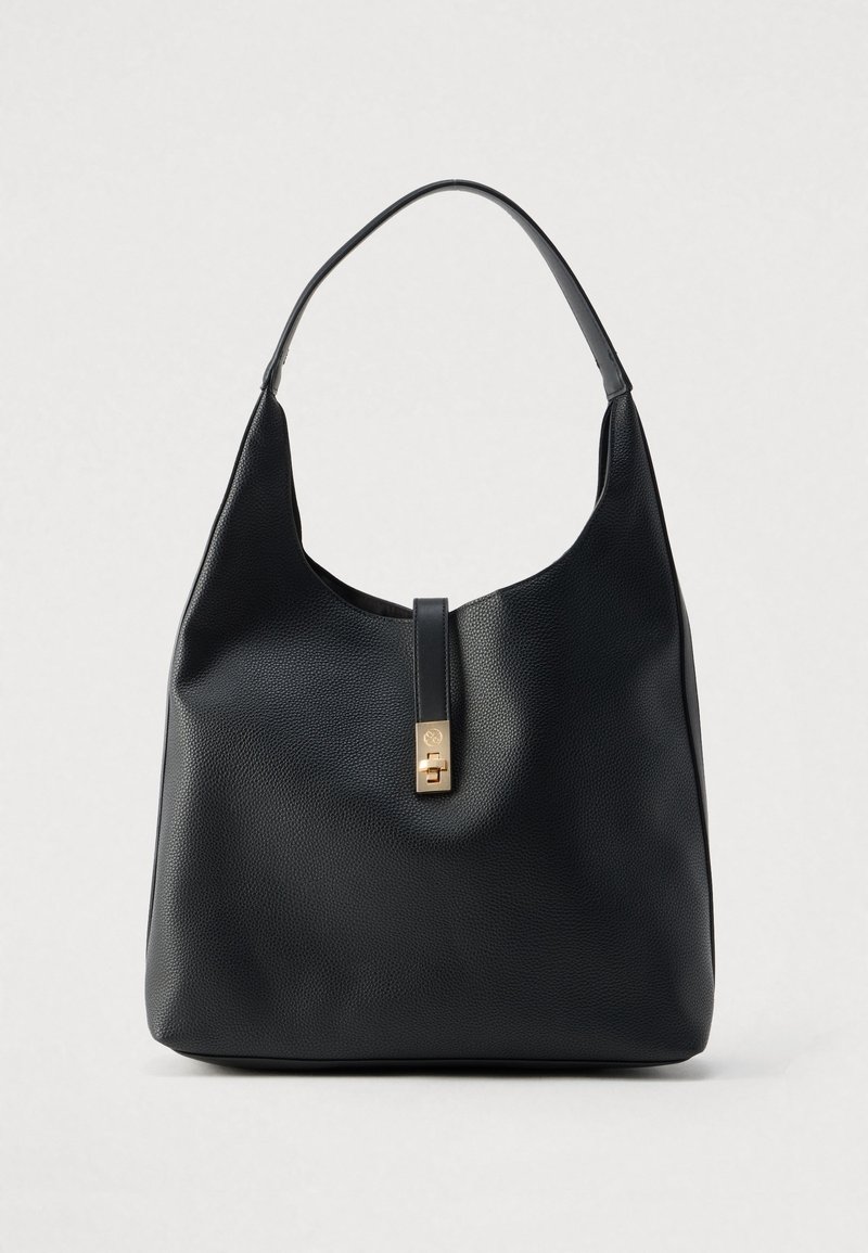 Sac à main en cuir noir texturé avec une bandoulière simple et un fermoir doré sur la sangle avant, sur fond uni.