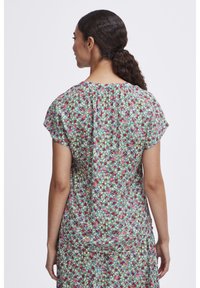 Robe à manches courtes à motifs floraux avec un fond vert, présentant une variété de fleurs colorées. Tissu doux, coupe décontractée et encolure froncée.
