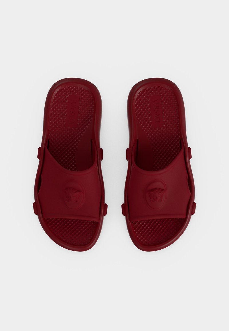 Pair of dark red open-toe slip-on sandals with textured footbeds and a logo embossed on the upper straps, shown from above on a plain background.