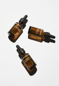 Three amber glass dropper bottles with black droppers and labels in white text; the label reads "Grown Alchemist" and product details.