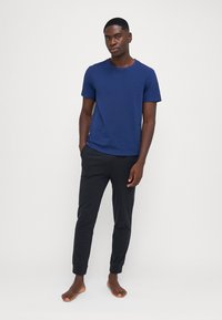 Marineblå kortermet t-skjorte kombinert med svarte tapered joggebukser. T-skjorten har rund hals, og buksene har ribbede mansjetter.