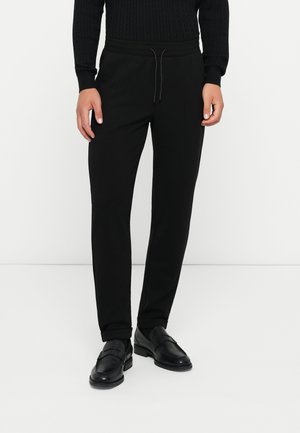 Pantalones deportivos negros en un diseño ajustado, con una cinturilla elástica y cordón, fabricados en una tela suave con una textura lisa.