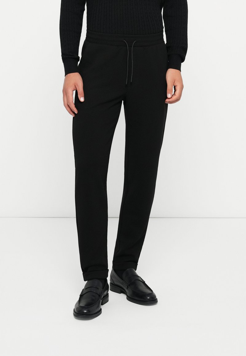 Schwarze Jogginghose im Slim-Fit-Design, ausgestattet mit einem elastischen Bund und Zugband, aus weichem Stoff mit glatter Textur.