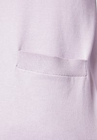 Light purple knit fabric featuring a patch pocket and ribbed hem detail. Smooth texture with a soft, minimal design.