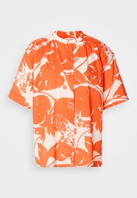 Blouse à manches courtes avec un motif floral audacieux orange et blanc, encolure ronde et détail froncé aux épaules.