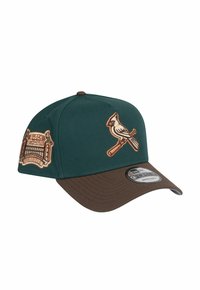 Casquette de baseball verte et marron avec un logo cardinal brodé et un patch "Busch Stadium". Présente un devant structuré et une visière courbée.
