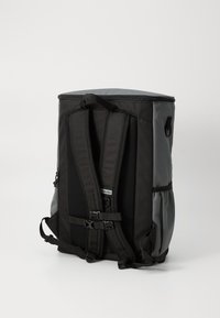 Black backpack with mesh straps, zip closure, and side pocket. Features a smooth top and durable fabric, suitable for outdoor use.
