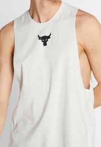 Camiseta sin mangas de color gris claro con escote redondeado, que presenta un logo de toro negro en el pecho. Fabricada con un tejido suave y texturizado.