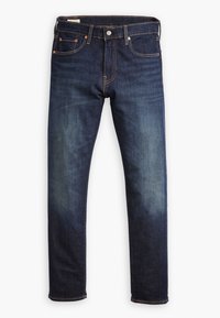 Jean en denim bleu foncé avec légère décoloration sur les cuisses, style cinq poches, fermeture par bouton et fermeture éclair, et rivets en cuivre aux coins des poches.