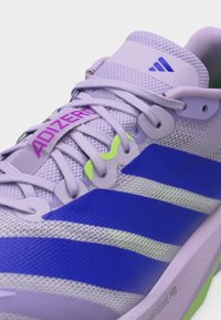 Gros plan sur une chaussure de course Adidas Adizero de couleur violet clair avec des rayures bleues, un logo rose et des accents vert néon sur les lacets et la semelle.