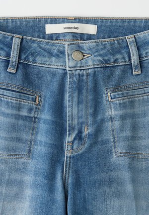 Hellblaue Jeans aus Denim mit glatter Textur, Fünf-Taschen-Design, sichtbaren Nähten und silberner Knopfverschluss. Das Etikett trägt die Aufschrift "someday".