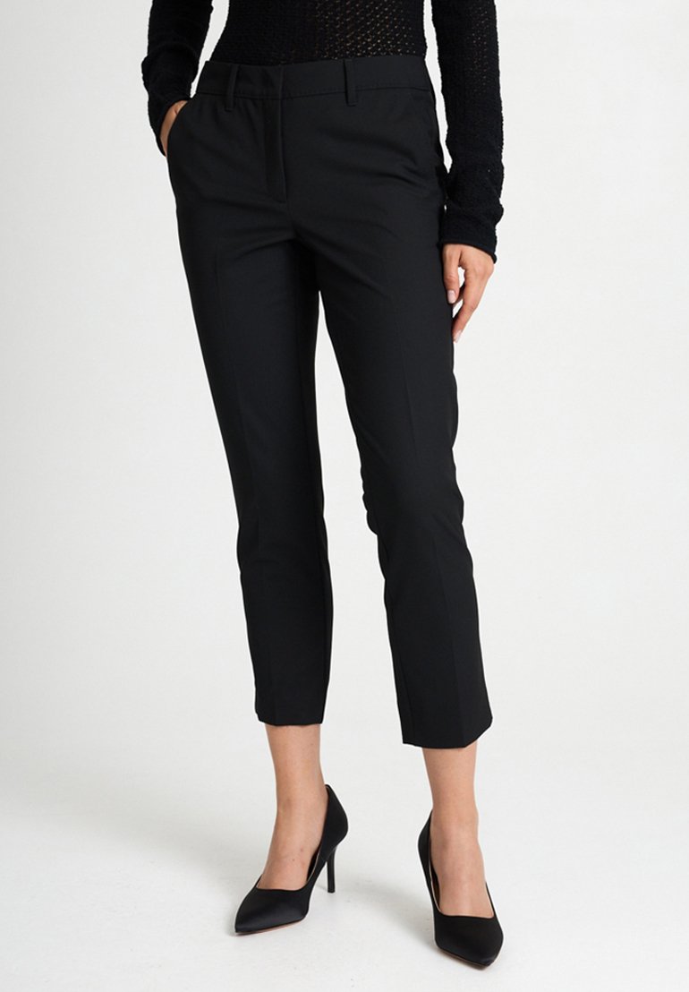 Pantaloni neri su misura con vestibilità slim, lunghezza cropped e texture liscia, abbinati a scarpe con tacco alto nere.