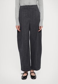 Pantalons à jambes larges en tissu gris foncé avec des rayures fines. Dotés d'une taille haute et d'une jambe droite, associés à des ballerines noires.