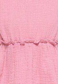 Tissu rose texturé avec un détail élastique froncé créant de doux plis verticaux et une bande horizontale volantée au centre.