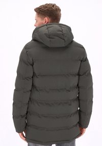 Ocieplana ciemnozielona parka z kapturem, z poziomymi pikowanymi sekcjami i miękką teksturą. Widoczne przeszycia podkreślają szwy.