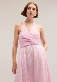 Rochie roz cu guler halter, cu dungi verticale albe, având un design înfășurat, bodice ajustat și fustă fluidă, realizată dintr-un material ușor.