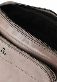 Borsellino in pelle marrone con superficie texturizzata, chiusura con cerniera superiore e un distintivo logo a ancora. Interno foderato in tessuto nero.