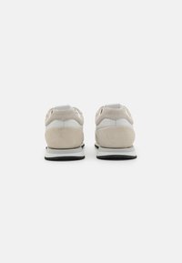 Beige og hvite joggesko med overdel i semsket skinn, polstret hæl og gummisåle. Minimalistisk design med kontrasterende teksturer.