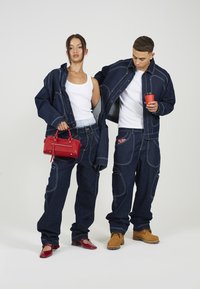 Denim jakne in hlače v temno modri barvi s poudarjenim belim šivom. Rdeča torbica, rdeče balerinke in svetlo rjave škornje. Prijetno, široko prileganje.