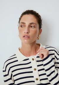 Randig stickad polo i krämfärg med marinblå ränder, med krage, tre guldknappar framtill och ribbade ärmslut.
