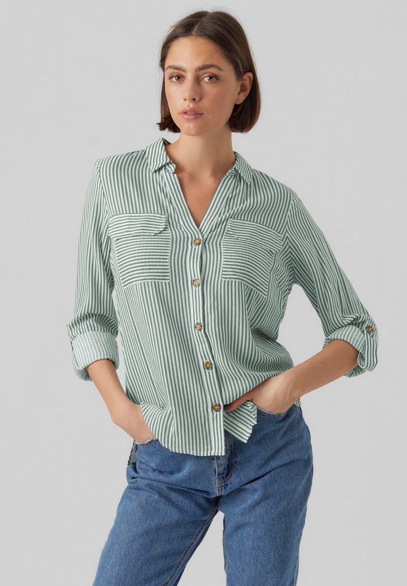 Light green striped button-up shirt with two chest pockets, rolled sleeves, and wooden buttons. Soft fabric with a relaxed fit.
